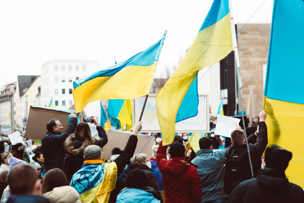 Folk demonstrerer med Ukrainske flagg. foto